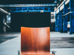 brown wooden chair with black metal base on gray pavement