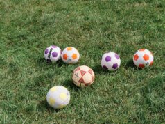 a group of soccer balls sitting on top of a lush green field
