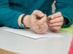 a person sitting at a table writing on a piece of paper