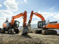 A group of construction equipment sitting on top of a dirt field