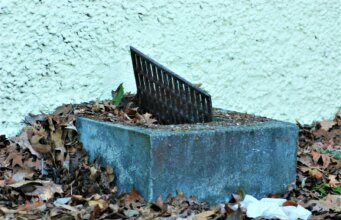 a metal grate sitting on top of a pile of leaves