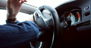 man holding black steering wheel