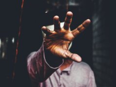 selective focus photography of man raising his right hand during daytime