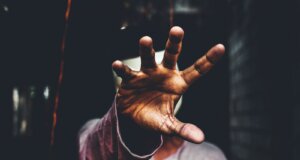 selective focus photography of man raising his right hand during daytime