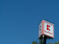 a red and white sign and some trees and a blue sky